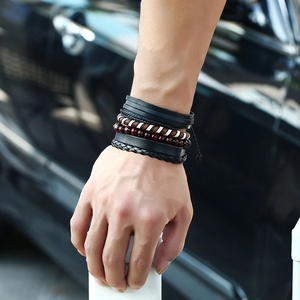 Men's retro layered woven leather bracelet set with beads worn on wrist in city setting