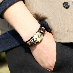 Close-up of Gemini zodiac leather bracelet featuring vintage metal charm and woven layers