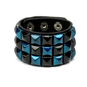 Detailed view of punk leather bracelet with blue and black pyramid studs and snap buttons
