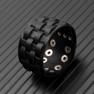 Detail of woven black leather wide bracelet with adjustable silver metal snap buttons
