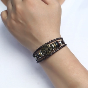 Detail view of a men's multi-layer woven leather bracelet with vintage bronze charms