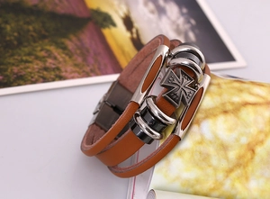Detail of vintage multilayer brown leather bracelet with cross charm and metal beads
