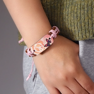 Handmade woven leather peace sign bracelet with adjustable cord worn on a wrist