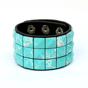 Detail of punk wide leather bracelet with triple row cyan square studs and snap closures