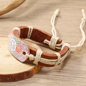Gros plan d'un bracelet en cuir bohème avec signe de paix floral sur une surface en bois