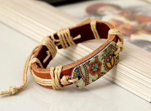 Vue macro d'un bracelet en cuir bohème avec un pendentif fleur et signe de paix coloré