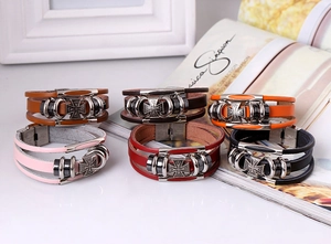 Close-up of assorted braided leather bracelets with iron cross metal charms and steel clasps