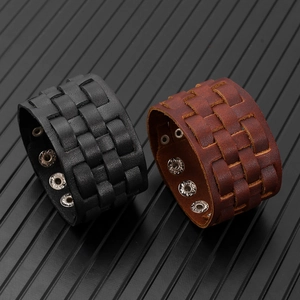 Detail of woven leather bracelets in black and brown with adjustable silver metal snaps