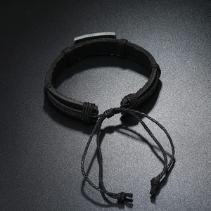 Detail of adjustable black leather bracelet with vintage metal plate and braided cord