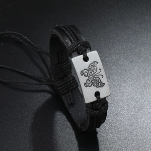 Detail of adjustable leather bracelet with butterfly engraved metal plate and braided rope
