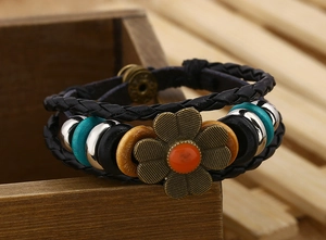 Dettaglio di bracciale bohémien multistrato in pelle con fiore di bronzo e perline turchesi