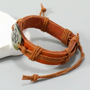 Macro detail of hand-braided leather bracelet with bronze Om charm on stone