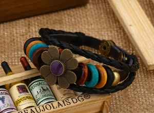 Dettaglio del bracciale in pelle intrecciata vintage con girasole e perline colorate