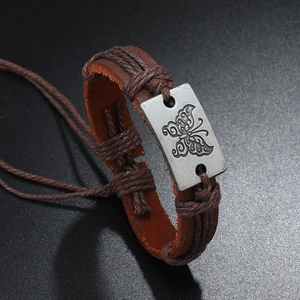 Macro detail of brown leather bracelet featuring butterfly embossed metal plate