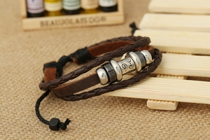 Dettaglio di un bracciale in pelle multistrato con cordoncino intrecciato e perline incise