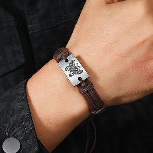 Vintage dark brown leather bracelet with butterfly engraved metal plate on a model's wrist