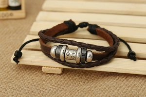Dettaglio di un braccialetto in pelle multistrato con perle metalliche vintage su legno