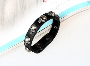 Detail of black leather punk bracelet with silver skull charms and double snap buttons
