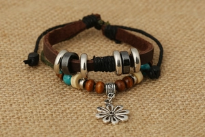 Dettaglio di un bracciale boho multistrato in pelle con perline turchesi e ciondolo a fiore in lega