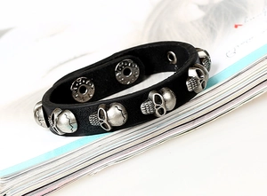 Detail of black leather punk bracelet with silver skull rivets and double snap closures