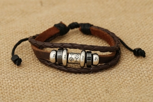 Dettaglio di un bracciale in pelle multistrato con perline vintage su lino rustico