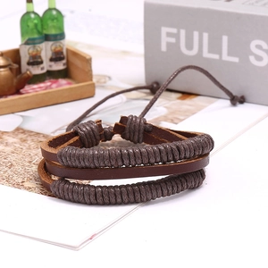 Dettaglio macro del bracciale in pelle intrecciata marrone scuro con cordini regolabili