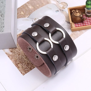Detail shot of a dark brown punk leather cuff bracelet with silver rings and metal studs