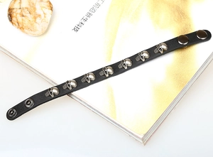 Close-up of black leather punk bracelet with nine silver skull studs and snap buttons
