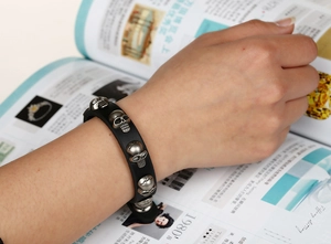 Detail shot of black leather punk bracelet featuring five vintage silver skull rivets