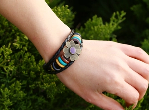 Dettaglio di un bracciale multistrato in pelle boho con fiori di bronzo e perline