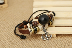 Detail of multi-layer leather bracelet featuring a silver nautical anchor charm and beads