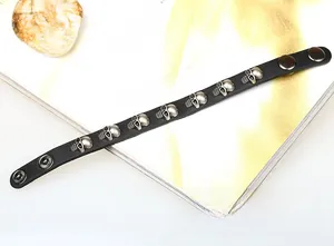 Detail of punk black leather bracelet with silver skull studs and metal snap closure