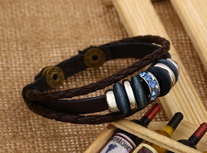 Dettaglio macro di un bracciale multistrato in pelle marrone con perline blu su lino