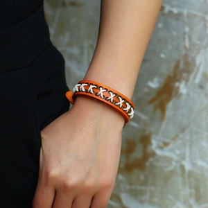 Orange braided leather bracelet for men with white cross-stitch detail and metal buckle