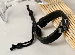 Détail d'un bracelet en cuir noir vintage avec breloque étoile croisée sur bambou