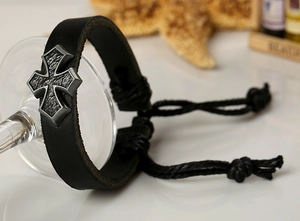 Détail d'un bracelet en cuir noir avec une croix en argent antique et cordon réglable