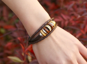 Dettaglio di un bracciale multistrato in pelle intrecciata con perline di legno e strass