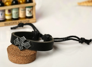 Détail d'un bracelet en cuir noir avec croix en métal vintage et cordon réglable