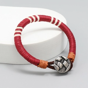 Détail d'un bracelet tissé en corde de cire rouge et blanche avec cuir brun et fermoir métal