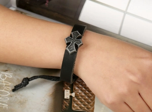 Gros plan sur bracelet en cuir noir avec croix en métal vintage et cordon réglable