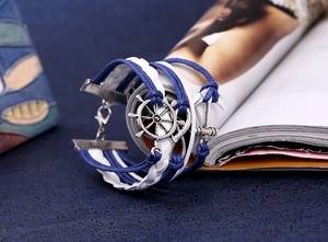 Detailed view of nautical multi-layer braided bracelet with anchor and rudder charms