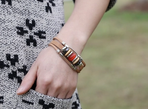 Close-up of vintage multilayer leather bracelet with orange bead and metal tube accents