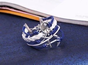 Detail of nautical multi-layer braided bracelet with anchor and rudder silver charms