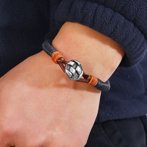 Détail du bracelet en cuir tressé à la main avec nœud orange et fermoir en métal argenté