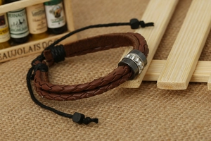 Macro detail of braided leather bracelet with crystal-studded metal ring on burlap background