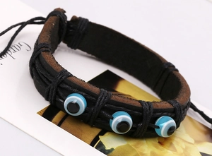 Détail d'un bracelet en cuir fait main avec trois breloques œil bleu et corde tressée