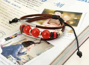 Close-up of multilayer leather beaded bracelet with brown straps and red beads