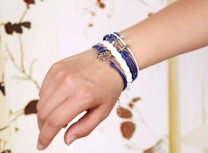 Detail of nautical layered bracelet with braided blue and white ropes and anchor charm