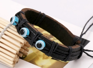 Détail du bracelet en cuir noir tressé avec trois perles bleues contre le mauvais oeil