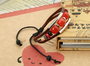 Close-up of multilayer vintage leather bracelet with large red beads and cord closure